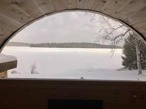 Vue hivernale sur un lac à travers la fenêtre en demi-lune d’un sauna