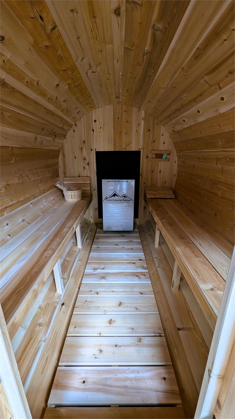 Intérieur d’un sauna en cèdre avec bancs et poêle à bois