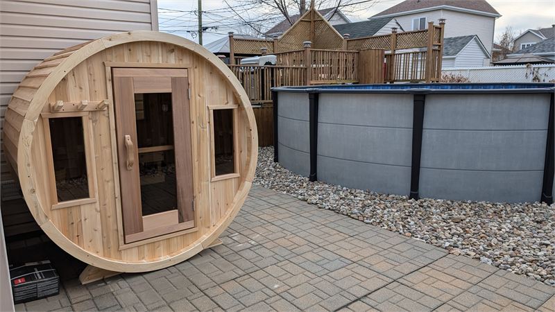 Sauna baril avec bancs sur le porche, sur une terrasse pavée