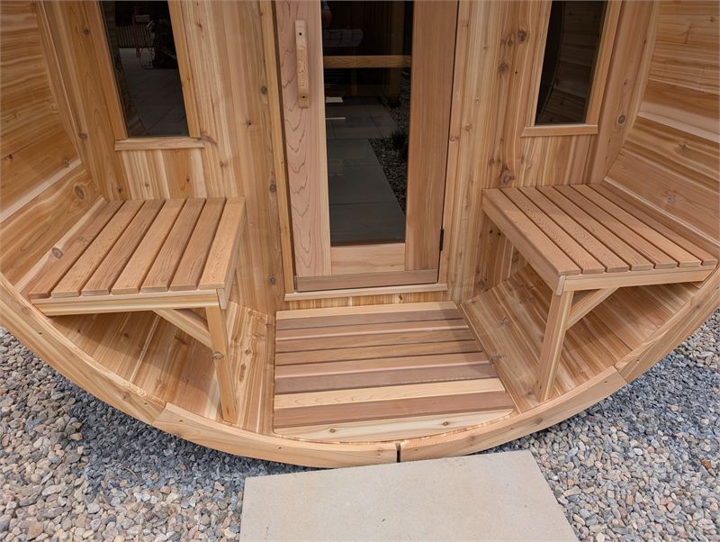 Porche d’un sauna baril avec bancs en cèdre et porte d’entrée vitrée