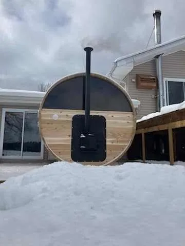 Barrel sauna with a wood-burning heater in winter