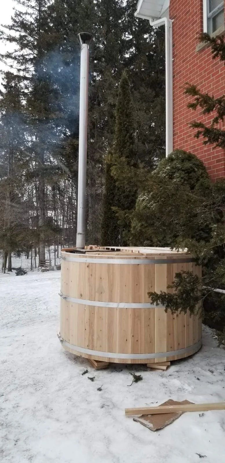 Cedar hot tub with a chimney in a winter setting